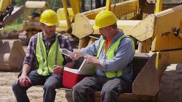 Two blue collar workers having lunch on job site video