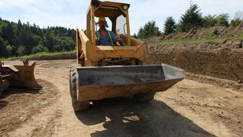 Trabajador de la construcción conduciendo equipos de excavación. video