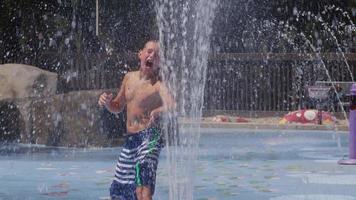 Children playing in water fountains on summer day, slow motion video