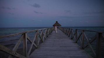 Woman walks down pier at tropical resort
