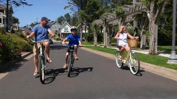 Familia montando bicicletas juntos en la comunidad de vacaciones costera. video