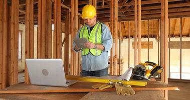 Trabajador de la construcción con tableta digital y computadora portátil video