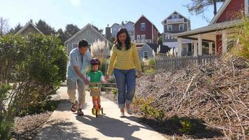 Parents walk with young child on scooter video