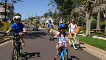 Familia montando bicicletas juntos en la comunidad de vacaciones costera. video