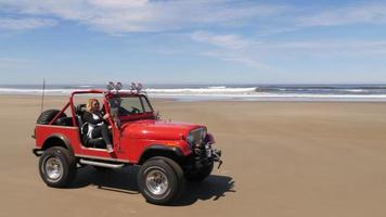 coppia alla guida di un fuoristrada 4x4 che guida sulla spiaggia video