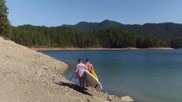 coppia che cammina in riva al lago con tavole da stand up paddle video