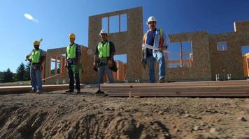 Grupo de trabajadores de la construcción de pie delante del sitio de trabajo video