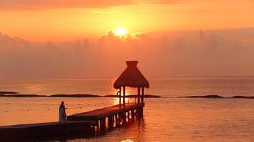 Woman walks along dock during sunset at tropical resort