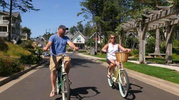Couple riding bicycles together in coastal vacation community video