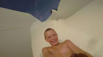 Young boy going down a waterslide at waterpark, POV video