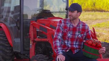 portret van boer zittend op tractor met mand met tomaten video