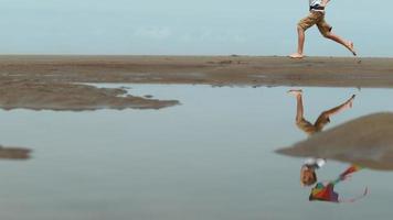 jongen loopt met vlieger op het strand, slow-motion video