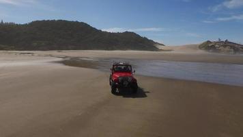 Toma aérea de un vehículo todoterreno 4x4 conduciendo en la playa video