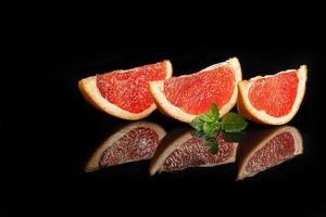 Slices of grapefruit on a dark background with a sprig of mint. photo