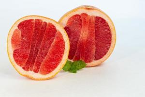 Grapefruit on a white plate with a sprig of mint. Isolate. photo