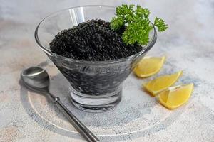 Black caviar in a dish on a light background. Healthy food concept. photo