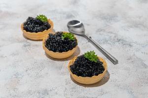 caviar negro en tartaletas sobre un fondo claro. concepto de comida sana. foto