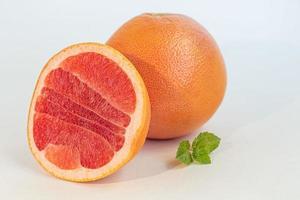 Grapefruit on a white plate with a sprig of mint. Isolate. photo