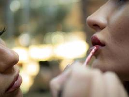 make up artist does make up to the young woman indoors.lips close up photo