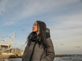 attractive young girl stands on the seashore and the sky photo