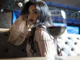 portrait of a beautiful brunette girl sitting with a glass of red wine photo