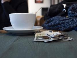 white cup of coffee on the table next to money and coins photo