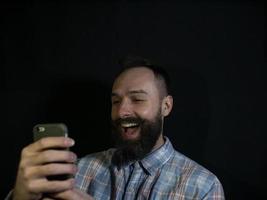 Hombre elegante con barba y bigote se ve en un teléfono móvil