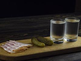 two misted glasses with cold vodka on a wooden board photo