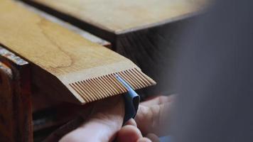 Tischler schleift mit Schleifpapier die Zähne auf einem Holzkamm video