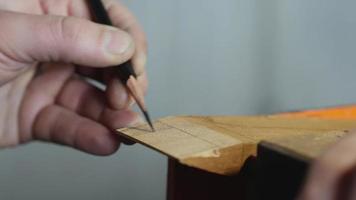 El artesano marca un trozo de madera con un simple lápiz.