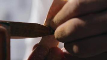 artisan grinds teeth on a wooden comb with sanding paper. video