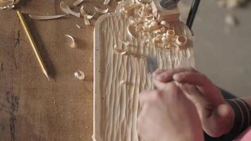 a woodcarver processes a pine wood board with a chisel