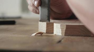 le sculpteur sur bois coupe les bords d'une planche de bois avec un ciseau plat video