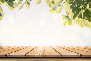 Empty wooden table over green tree in garden under sunrise. photo