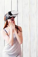 A girl wearing VR glasses, excitedly smiling, her hands at face photo