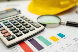 Calculator with yellow construction helmet on chart and graph paper. photo