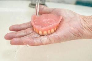 Asian senior woman patient holding partial denture teeth photo