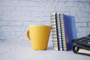 yellow color mug mockup with with notebooks on table