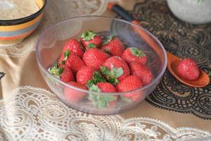 Fresas frescas en un recipiente sobre la mesa foto