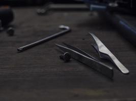 tweezers and an allen key lie on a wooden table. tools on the table photo