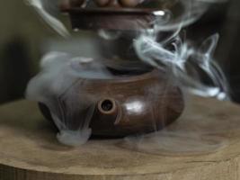 close-up male hand opens the lid of a clay teapot made photo