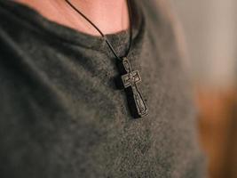 Cruz ortodoxa de madera colgando del cuello de un hombre foto