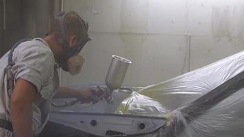 Process of car painting in workshop, worker in mask video