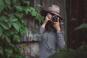 Beautiful woman in hat is taking picture with old fashioned camera photo