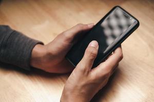 Man using smartphone on wooden table, searching, browsing, social photo