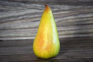 Yellow pear stands on a wooden background photo