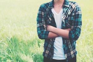 Happy man standing on the green grass with arms crossed. photo