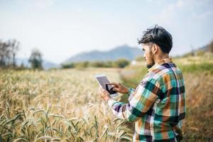 Granjero inteligente comprobando la granja de cebada con tablet PC foto