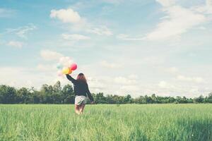 Back of happy young woman standing on green field enjoy with fresh air photo