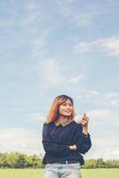 Young woman standing on grassland holding coffee and enjoy fresh air photo